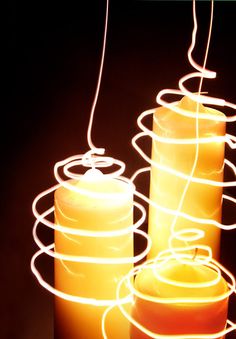 three lit candles sitting next to each other in front of a black background with white lines