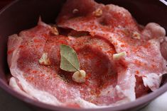 a bowl filled with meat and seasoning on top of a table