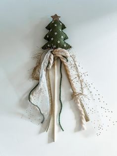 a small christmas tree made out of branches and ribbons on a white background with gold stars