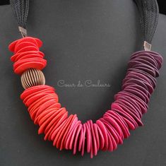 a necklace made out of red, pink and brown paper strips on a black background