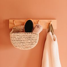 a basket hanging on the wall next to a towel rack with two hats in it