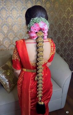 the back of a woman's head wearing a red sari with flowers in her hair