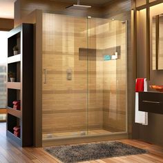 a bathroom with a glass shower door and wooden flooring, along with a rug on the floor