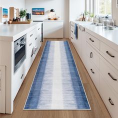 a kitchen with white cabinets and blue runner rug