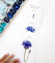 someone is painting flowers with watercolors on paper