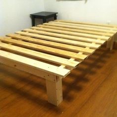 a wooden bed frame sitting on top of a hard wood floor next to a wall