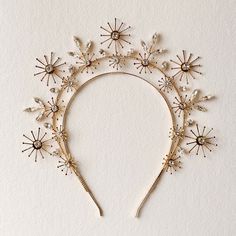 a headband with flowers and pearls on the side is made out of gold wire