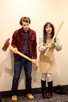 two people standing next to each other holding large hammers and an ax in their hands