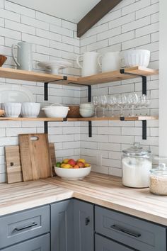 a kitchen with open shelving and wooden counter tops, white subway backsplash