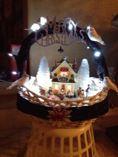 a lighted christmas village in the shape of a house on top of a basket with lights