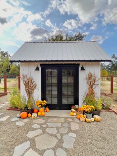 a small white building with pumpkins and gourds outside