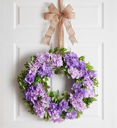 a wreath with purple flowers hangs on the front door