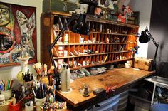 an art studio with lots of crafting supplies on the desk and shelves above it