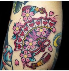 a woman's arm with tattoos on it and flowers in the center, holding an umbrella