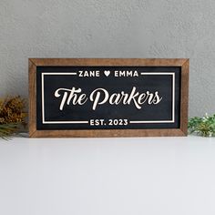 a wooden sign that says the parkers on it next to pine cones and evergreens