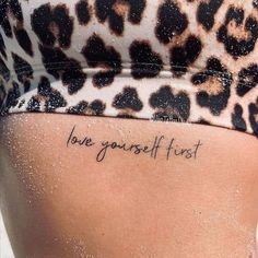 a woman's lower back tattoo with the words love yourself first written on it