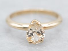 an oval shaped diamond ring with a gold band on top and bottom, sitting on a white surface