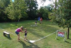 a woman and two children are playing in the park with a frisbee golf net