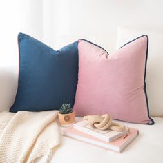 two pillows and a potted plant sit on a bed next to each other,