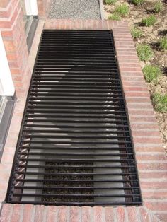 a drain hole in the side of a brick wall next to a sidewalk and grass