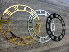 three different metal clocks on a wooden surface