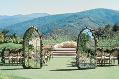 an outdoor ceremony set up with chairs and greenery on the lawn, overlooking mountains