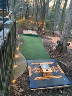 an outdoor miniature golf course with lights on the ground and trees in the backgroud