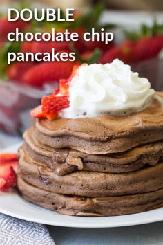 a stack of chocolate pancakes topped with whipped cream and strawberries