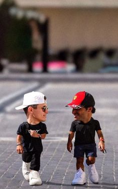 two small dolls are standing next to each other on the street, one is wearing sunglasses and the other has a baseball cap