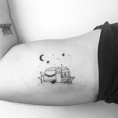 a black and white photo of a woman's arm with a small camper tattoo on it