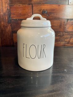 a white canister with the word flour written on it in cursive writing