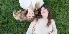 two women laying on the grass looking up