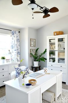 a living room with a white table and ceiling fan in the middle of the room