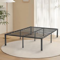 a metal bed frame sitting on top of a white rug in a living room next to a plant