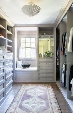 a walk - in closet with drawers, cabinets and rug