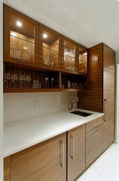 an empty kitchen with wooden cabinets and white counter tops in front of a wine glass cabinet