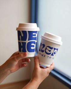 two people holding up coffee cups with the words nega on them, one to go