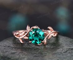 a ring with a green stone in the middle on top of a black rock,