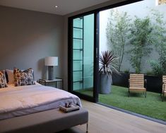 a white bed sitting in a bedroom next to a sliding glass door that opens onto a lush green yard