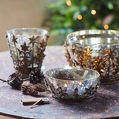 three glass bowls sitting on top of a table next to a christmas tree with lights in the background