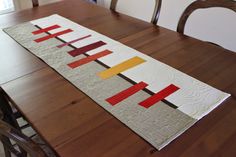 a wooden table topped with a long piece of art on top of a wooden dining room table