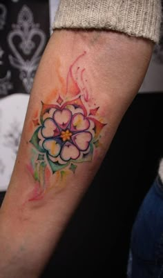 a colorful flower tattoo on the arm