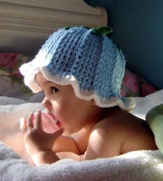 a baby wearing a knitted hat while laying on a bed