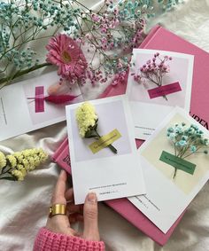 a person holding flowers on top of pink and white sheets with cards attached to them