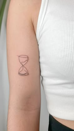 a woman's arm with a small hourglass tattoo on the left side of her arm