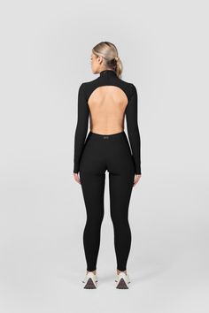 This full-length backless jumpsuit features perfectly placed cutouts for a figure-flattering silhouette. Fitted High Neck Athleisure Activewear, Athleisure Fitted Backless Bodysuit, High Neck High Stretch Elastane Unitard, High Neck Unitard With Thumbholes, Fitted Athleisure Bodysuit With Thumbholes, High Neck High Stretch Unitard For Night Out, Fitted Athleisure Backless Jumpsuits And Rompers, High Neck Unitard With High Stretch For Night Out, Sleek High Stretch Unitard For Night Out