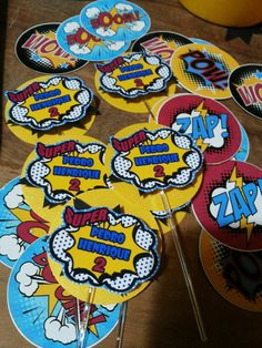 a table topped with cupcake toppers covered in comic character stickers and decorations