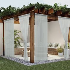 an outdoor living area with white curtains and plants on the roof, surrounded by grass