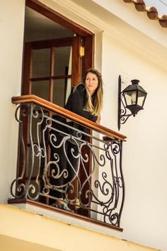 a woman is standing on the balcony looking out