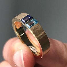 a man is holding his wedding ring with two blue stones on the inside of it